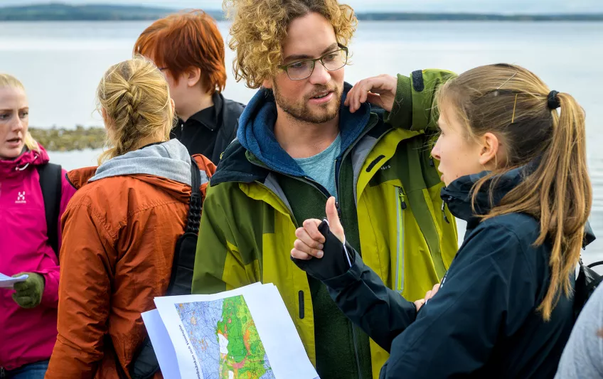 Två studenter diskuterar med sjö i bakgrunden. Foto: Kennet Ruona.